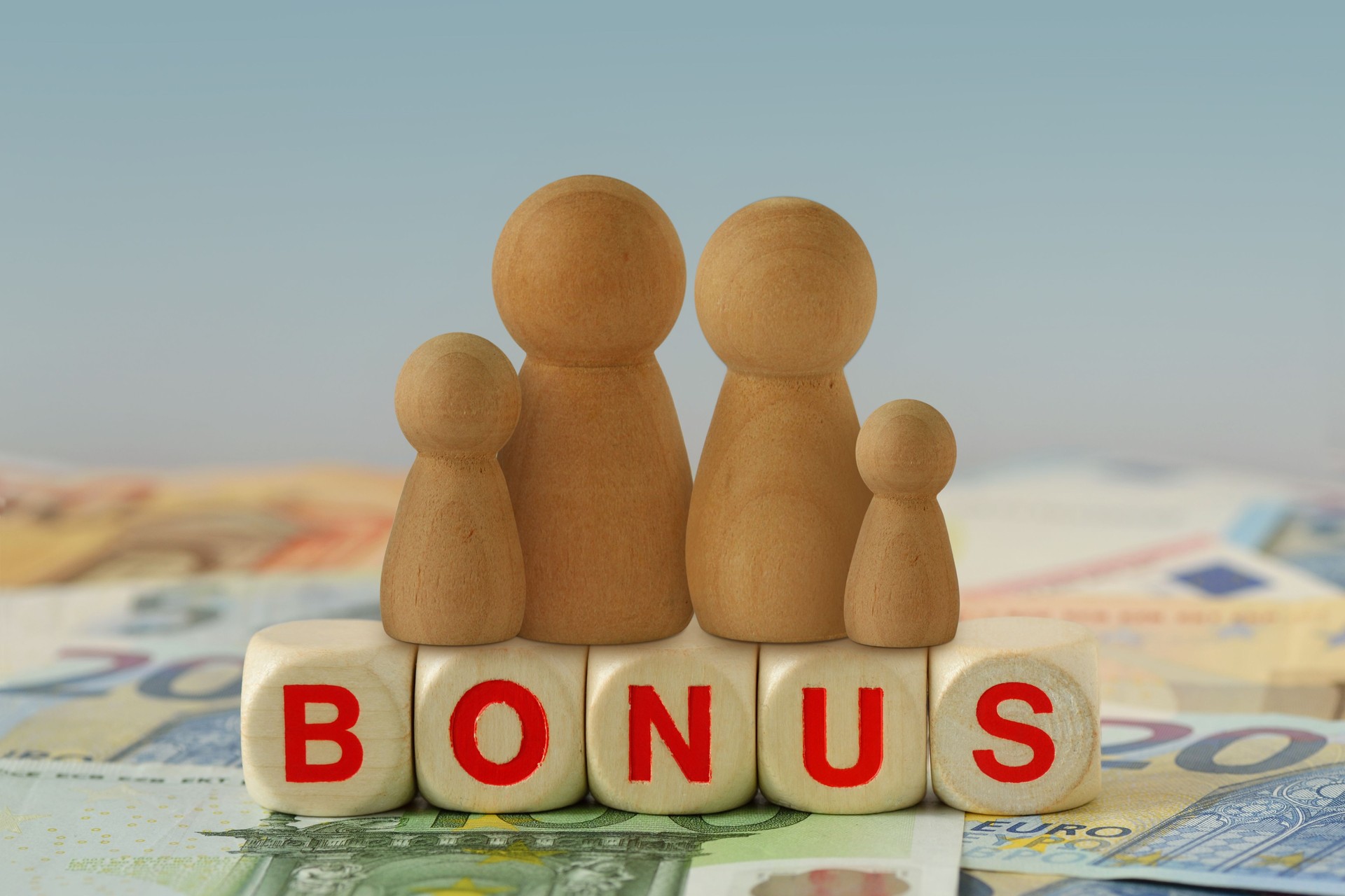 Family on wooden blocks with the word Bonus on euro banknotes - Concept of economic bonus and financial aid